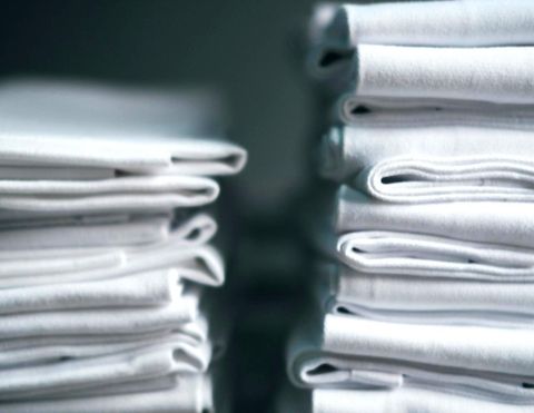 Neatly folded stacks of clean white linens, representing professional commercial laundry.