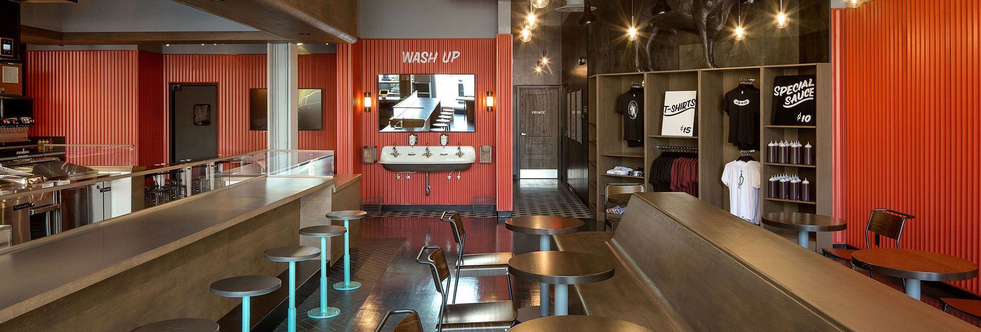 Interior of a modern bar with red walls, metal accents, and bar stools.