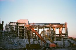 Building demolition with excavators, rubble, and a dusky sky.