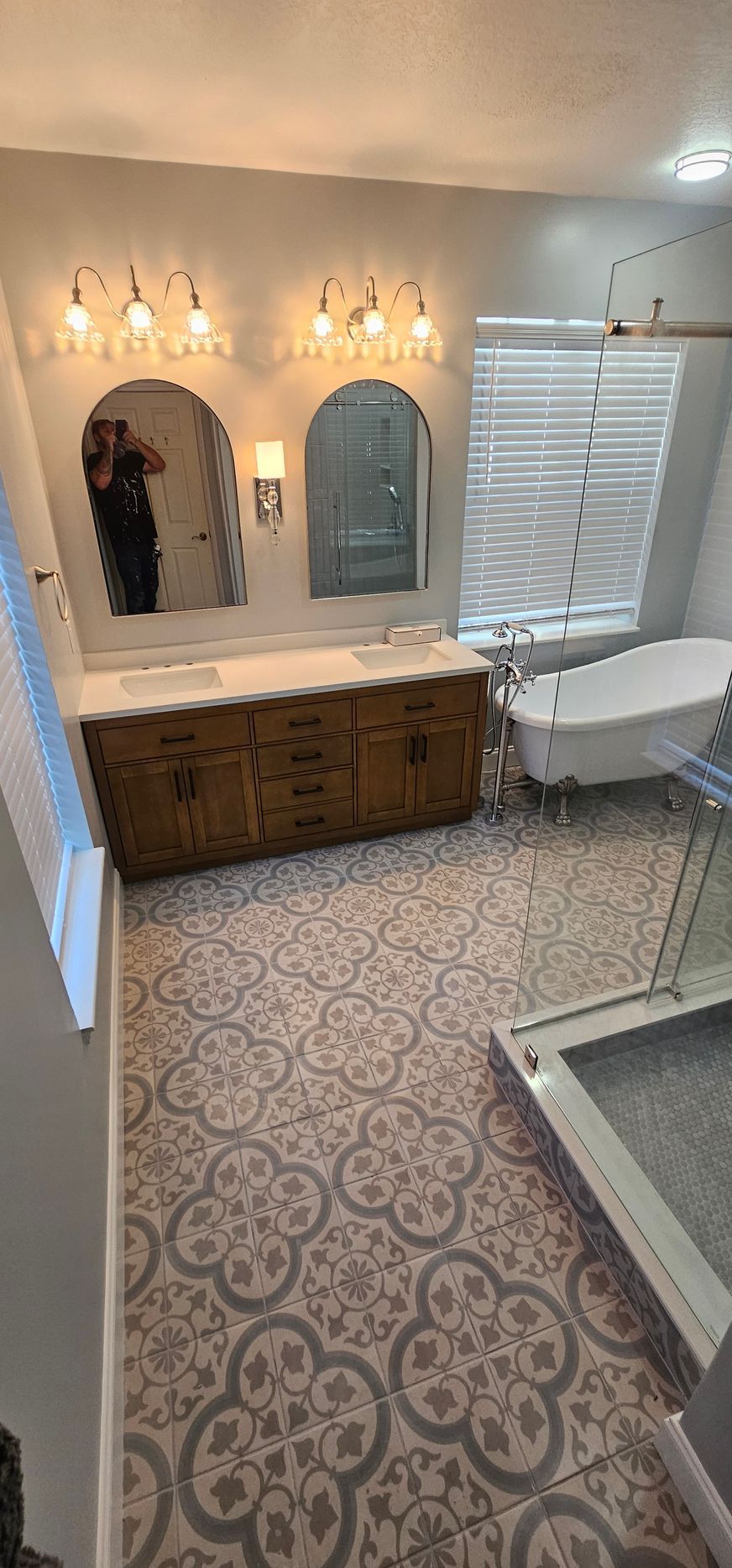 A living room with a couch , television , fireplace and white tiles on the floor.