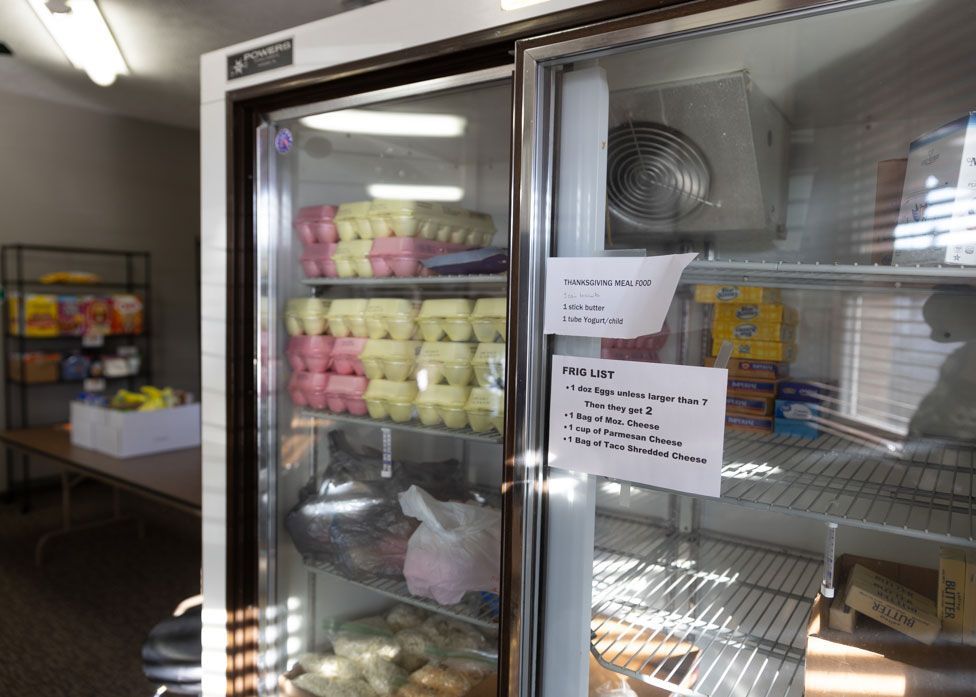A refrigerator filled with lots of food and a sign on the door.