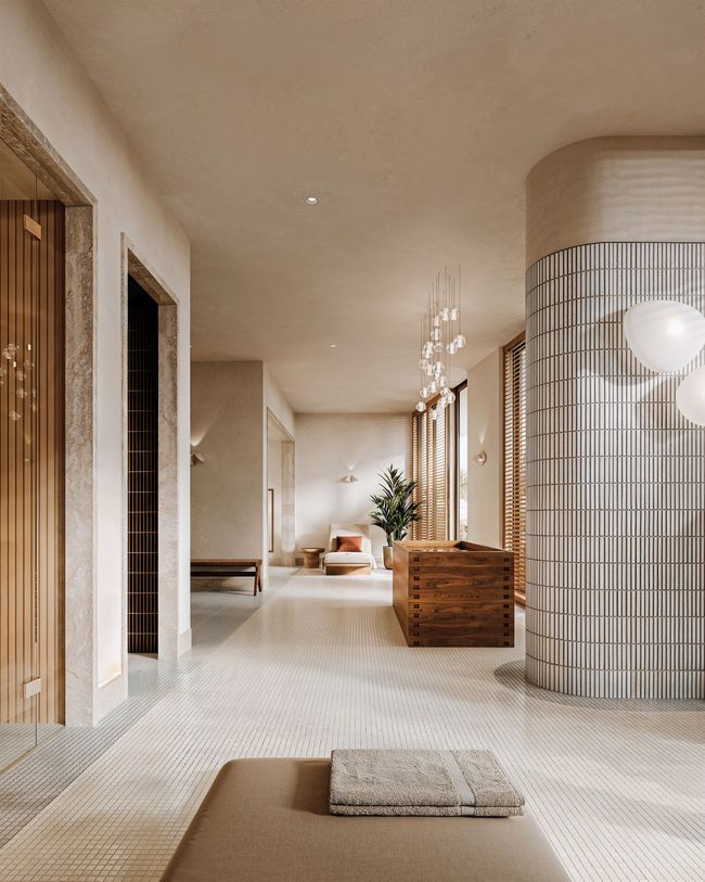 Sunlit outdoor patio with white walls, archways, green and white patterned floor, rattan chairs, and potted plants.