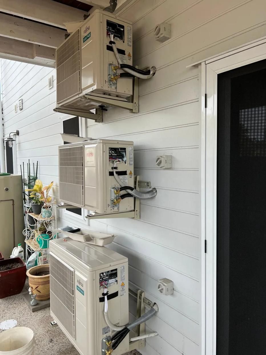 Two Air Conditioners Are Stacked on Top of Each Other on The Side of A Building — Next Level Resources In Rockhampton, QLD