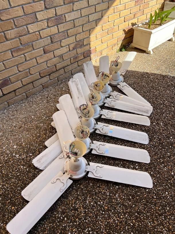 A Row of White Ceiling Fans Are Sitting on The Ground in Front of A Brick Wall — Next Level Resources In Rockhampton, QLD