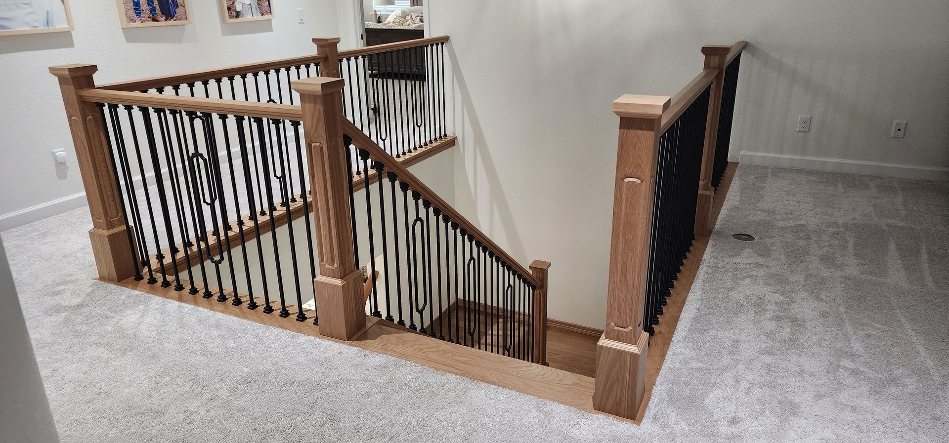 Staircase with wooden railing and black spindles, carpeted floor.