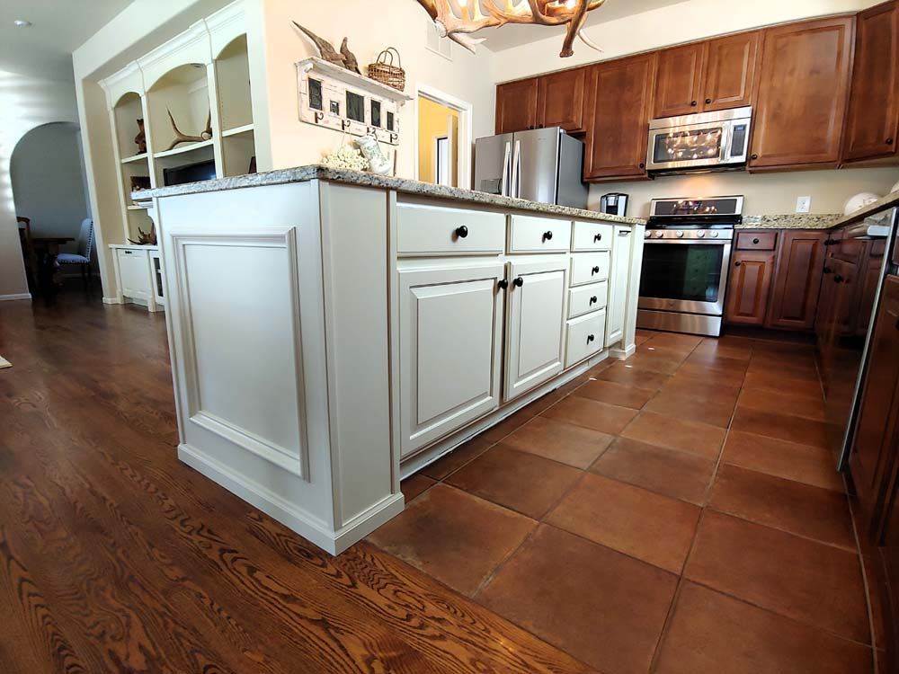 Kitchen with a white island, brown cabinets, and wood flooring.