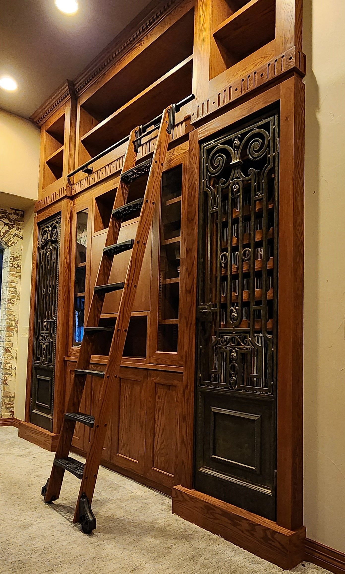 Wooden library shelves with a rolling ladder and a decorative door.