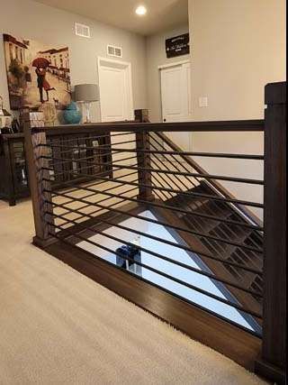Dark wood railing with black horizontal bars in a home's upper level.