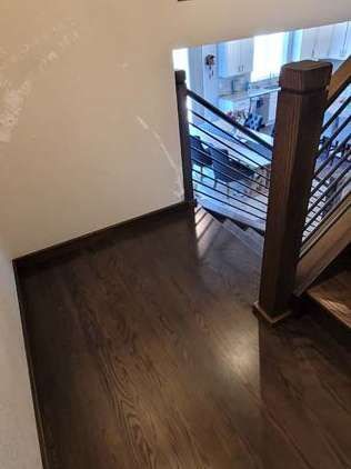 Staircase with dark wood flooring and railing, leading to a visible kitchen area.