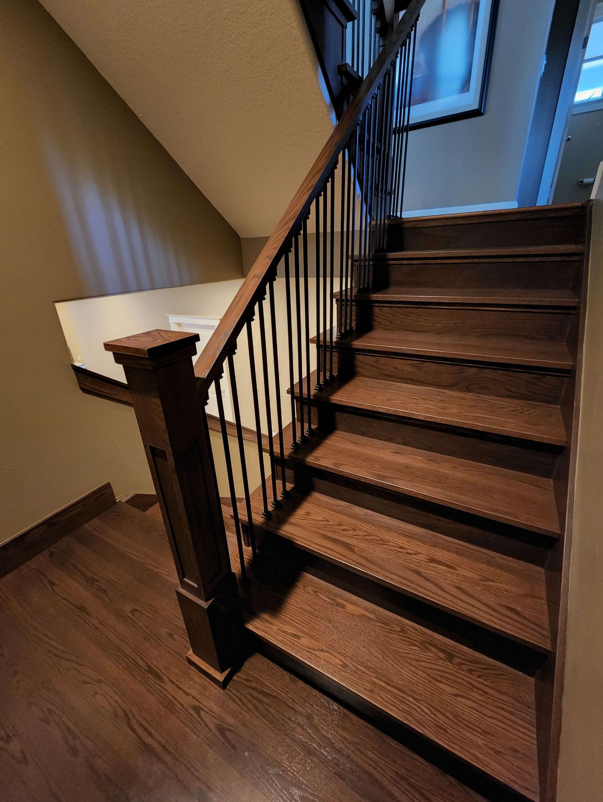 Wooden staircase with dark brown treads and black spindles.