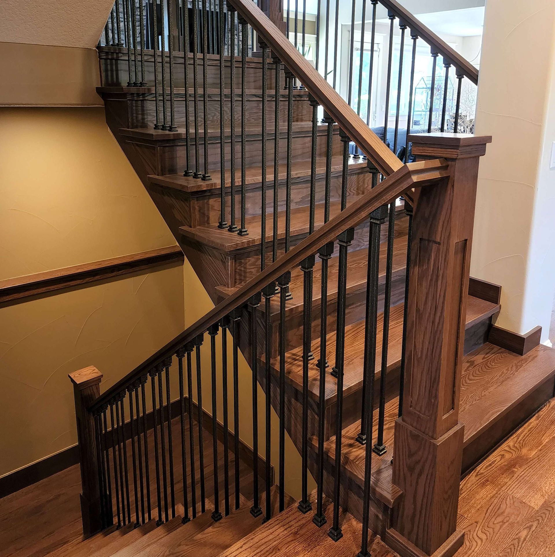 Wooden staircase with black metal balusters and oak handrails.