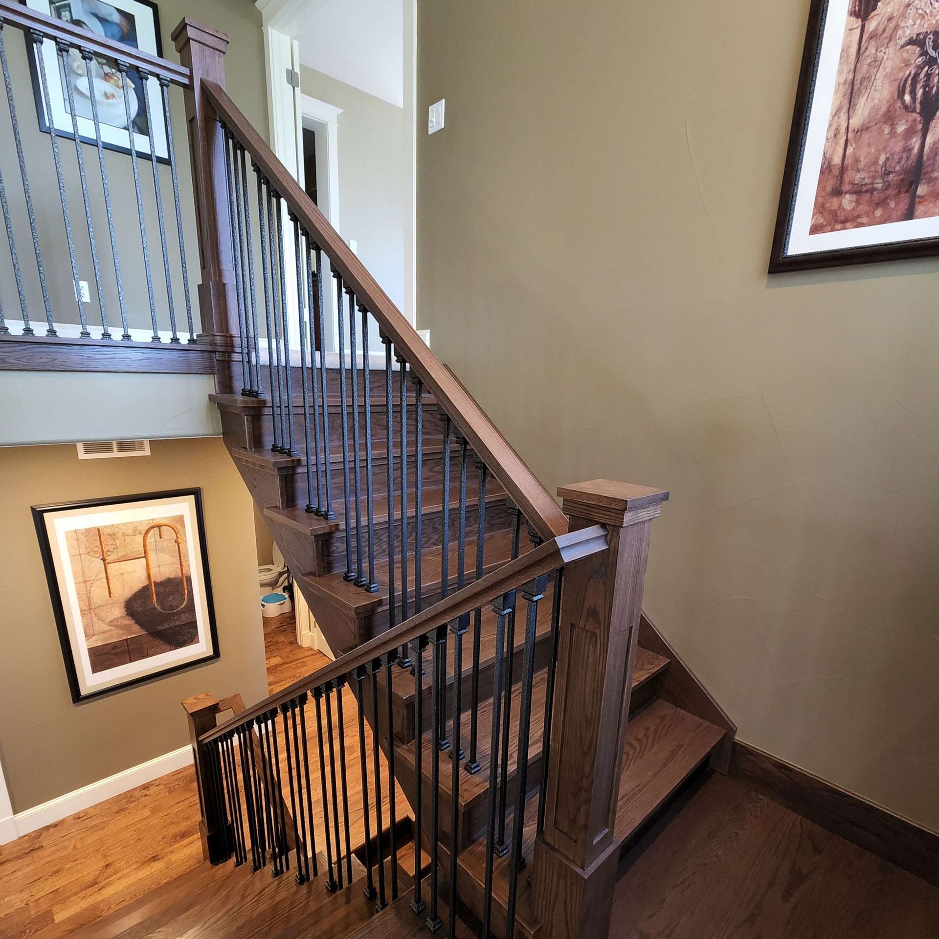 Wooden staircase with dark metal railings, brown treads, and tan walls.