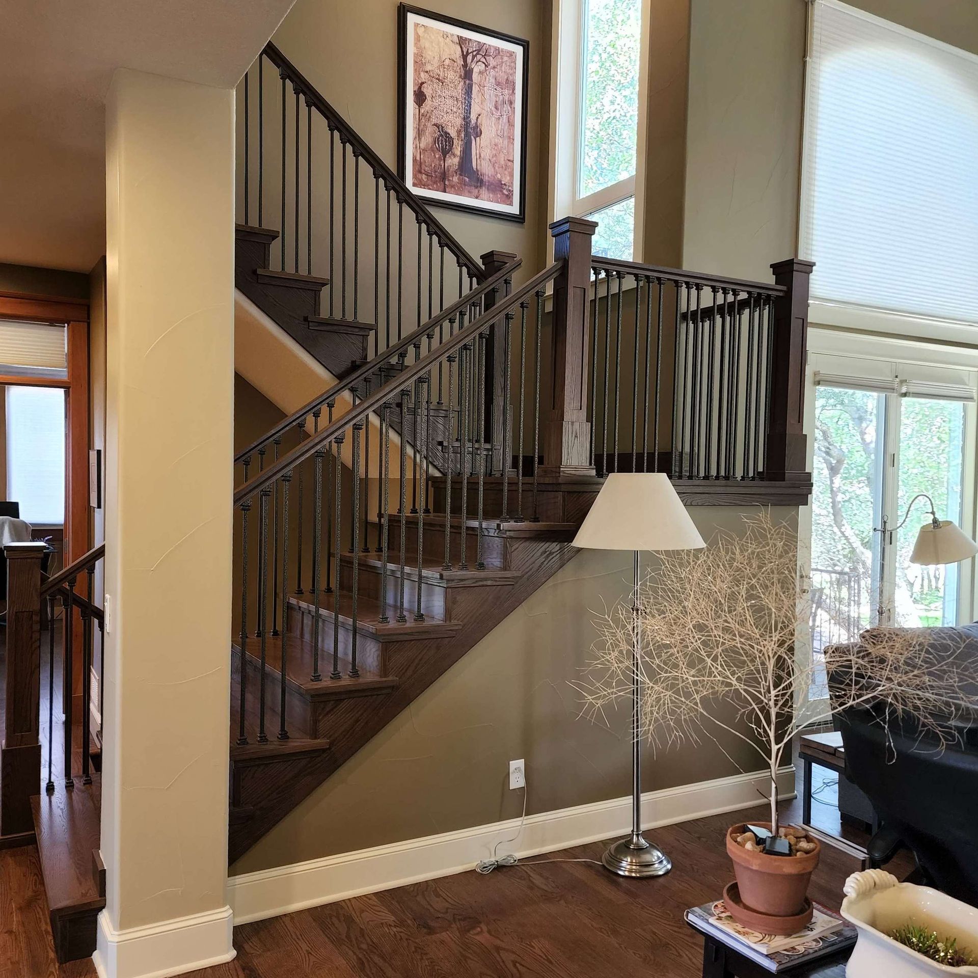 A two-story interior with a wooden staircase and a dark metal railing against an olive-colored wall.