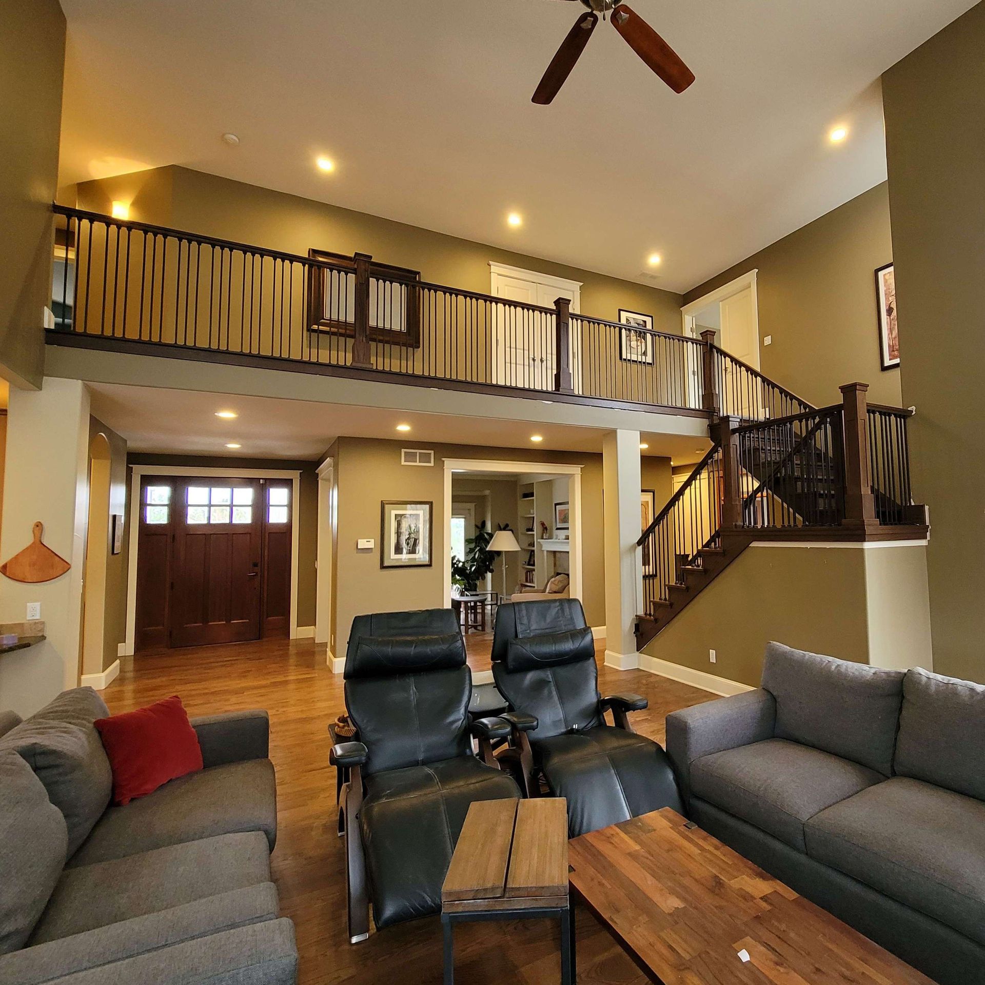 Living room with a loft, dark wooden staircase, and two reclining chairs.
