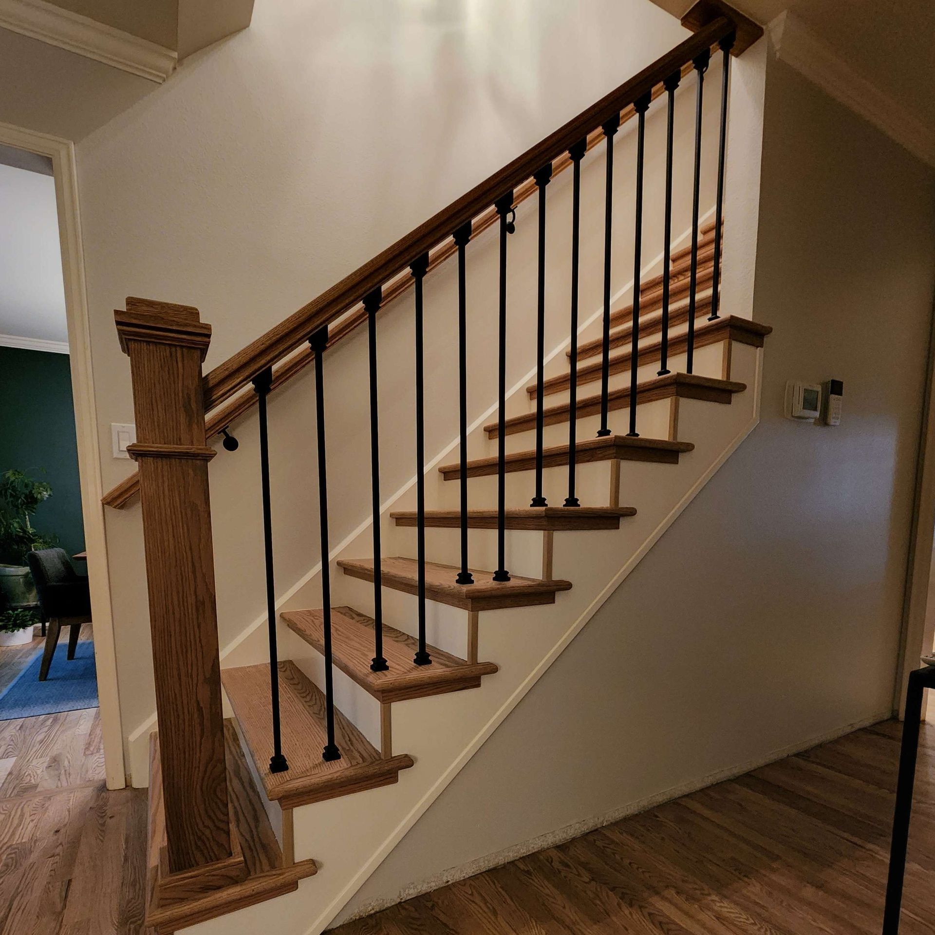 Wooden staircase with black metal spindles and wooden handrail and newel post.