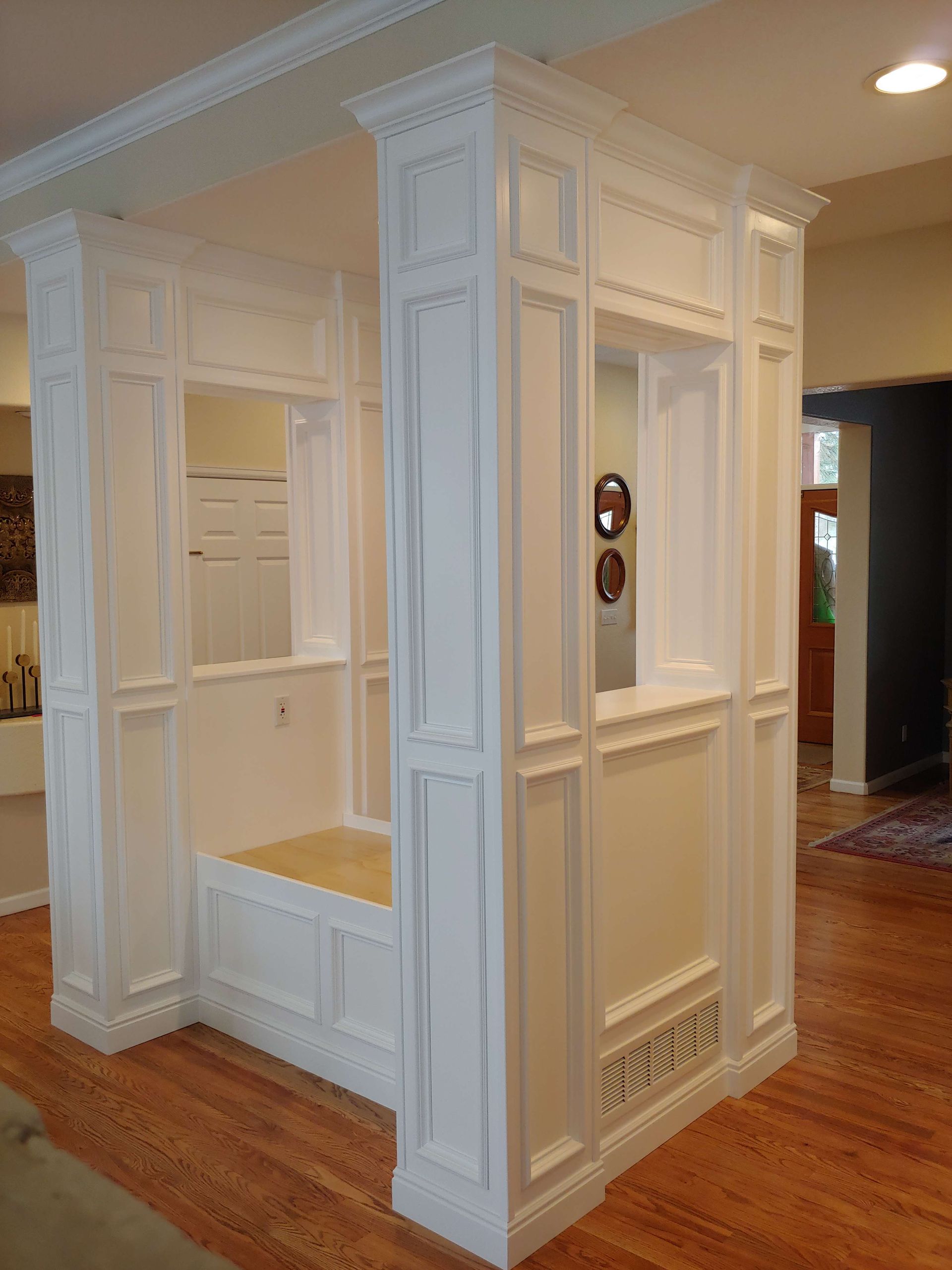 White paneled architectural structure with windows, built-in to a room with wood flooring.