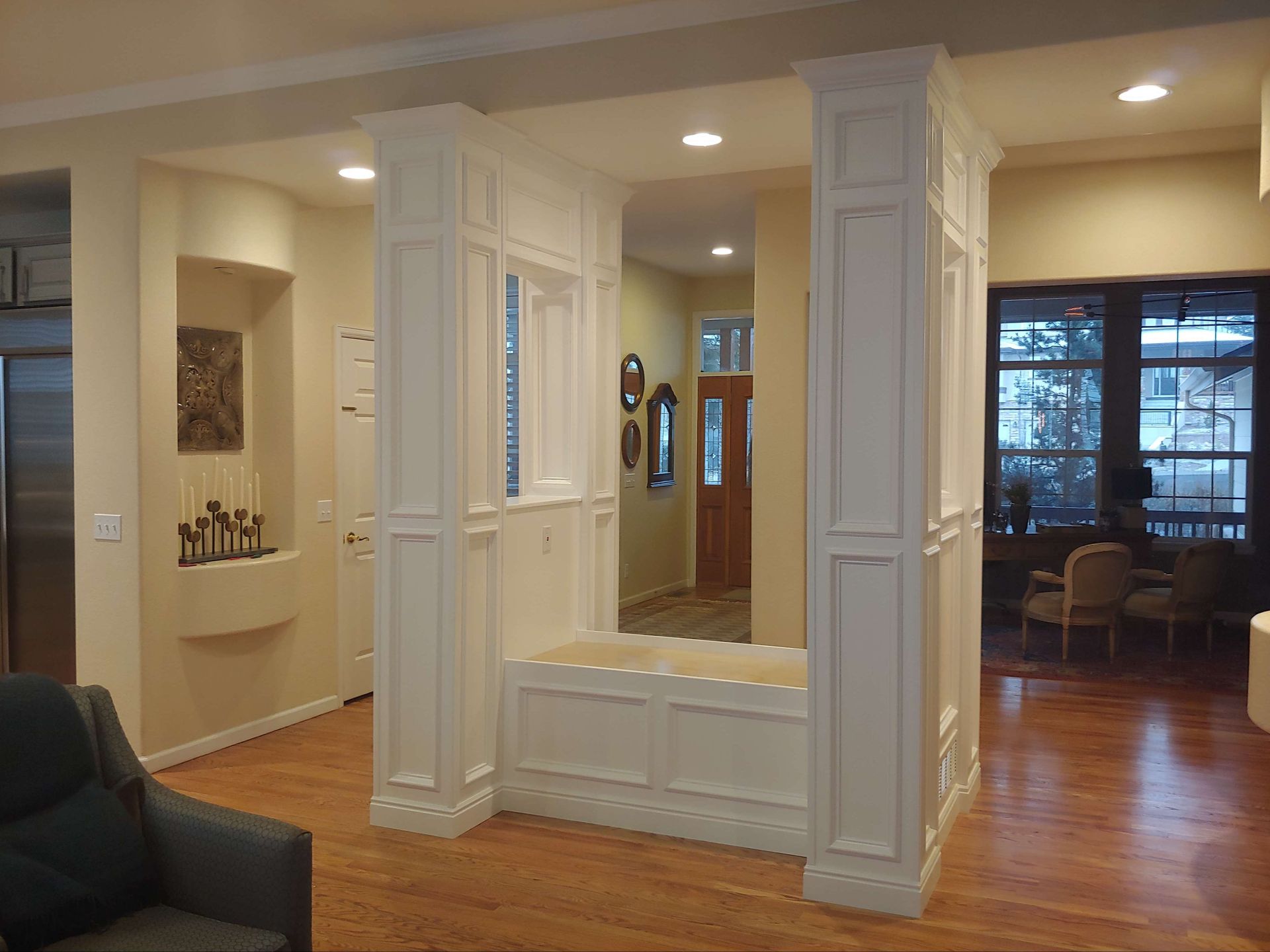 Interior with built-in bench and decorative columns. Wooden floors and walls are painted cream and off-white.