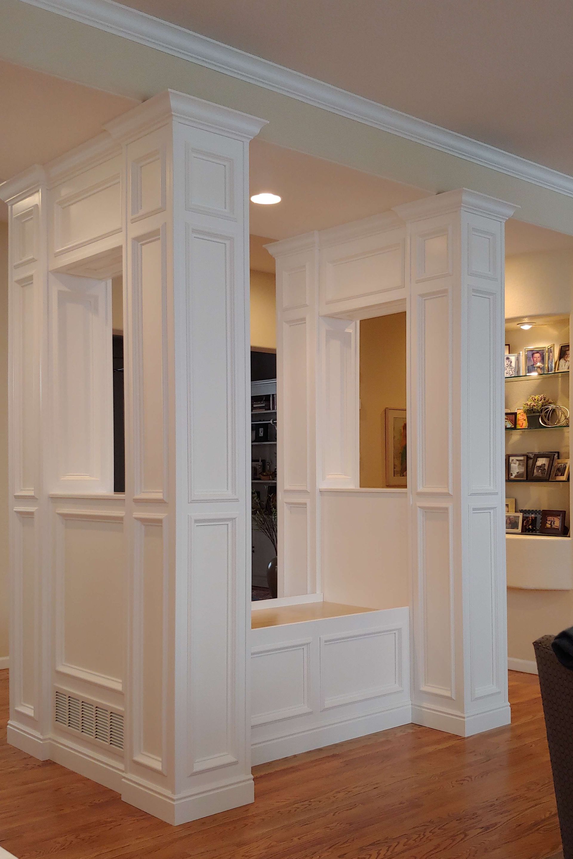 White paneled room dividers, built-in bench, with a light-colored wood floor.