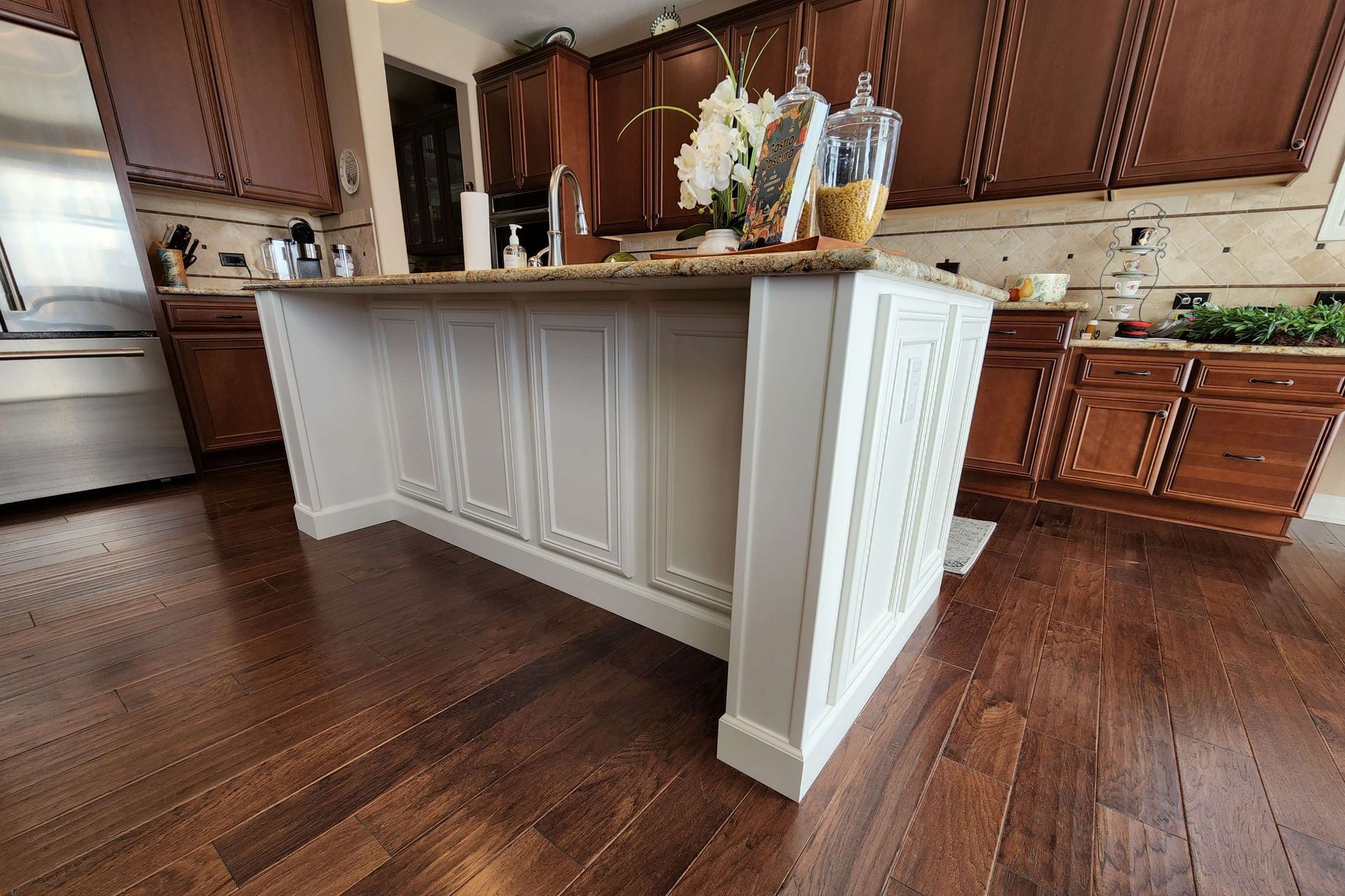 Kitchen island with white paneling and dark wood floors and cabinets.