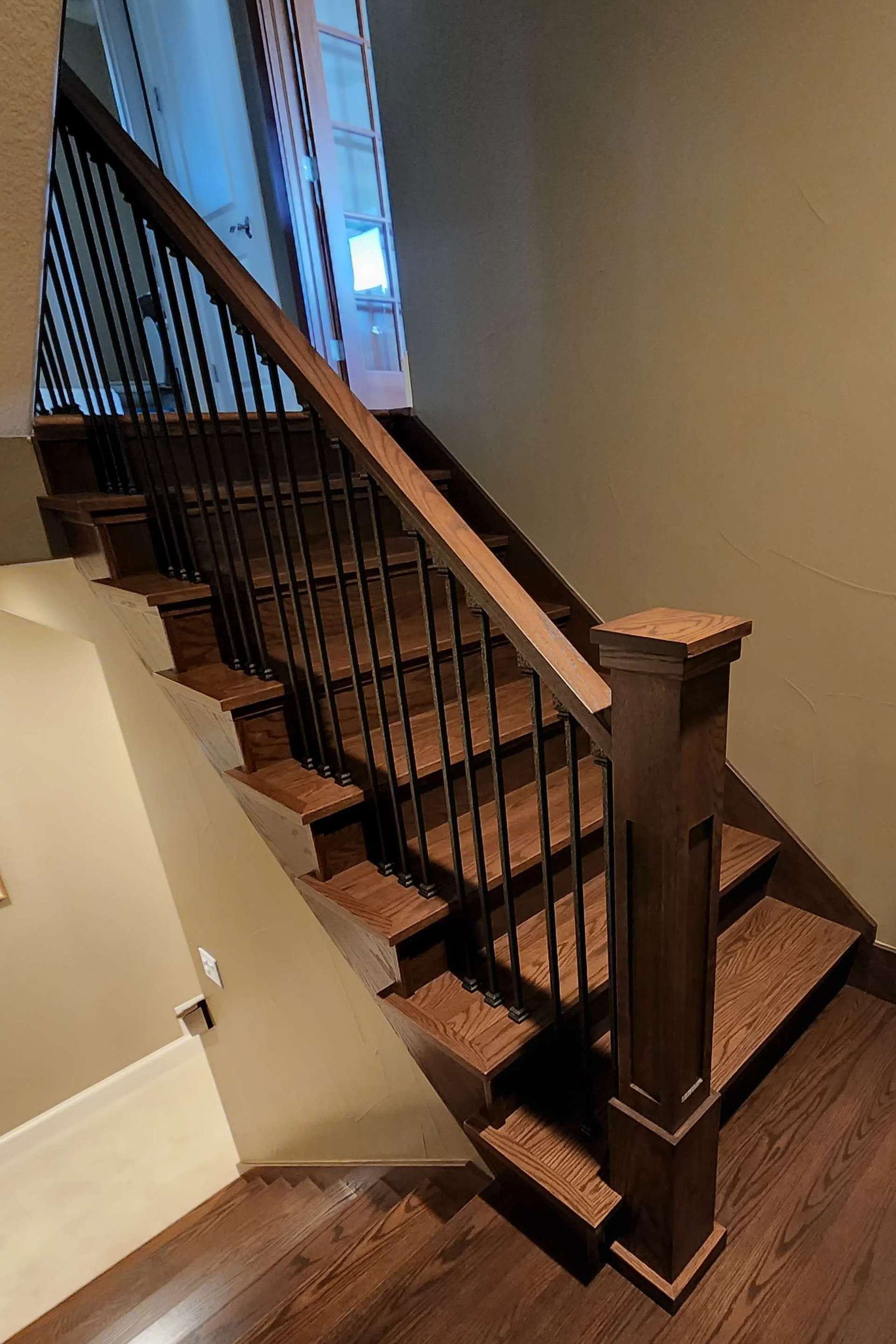 Wooden staircase with black metal balusters, stained dark brown.