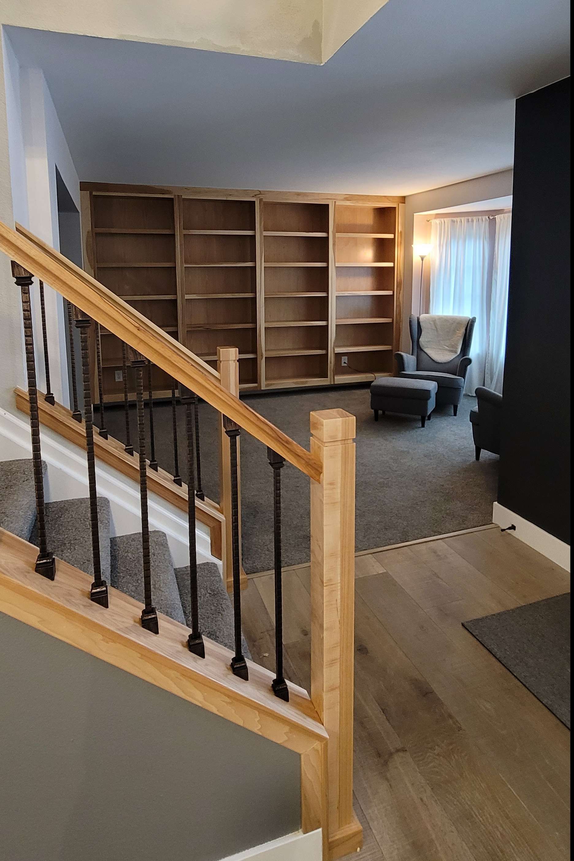 Staircase leading to a living room with built-in bookshelves, chair, and fireplace.