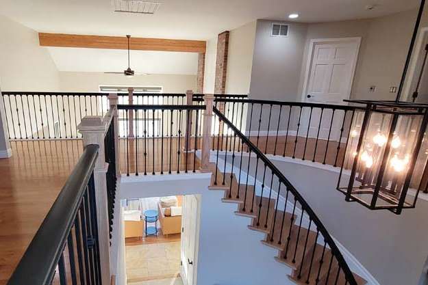 Interior view of a house with a curved staircase, hardwood floors, and a wrought-iron railing.