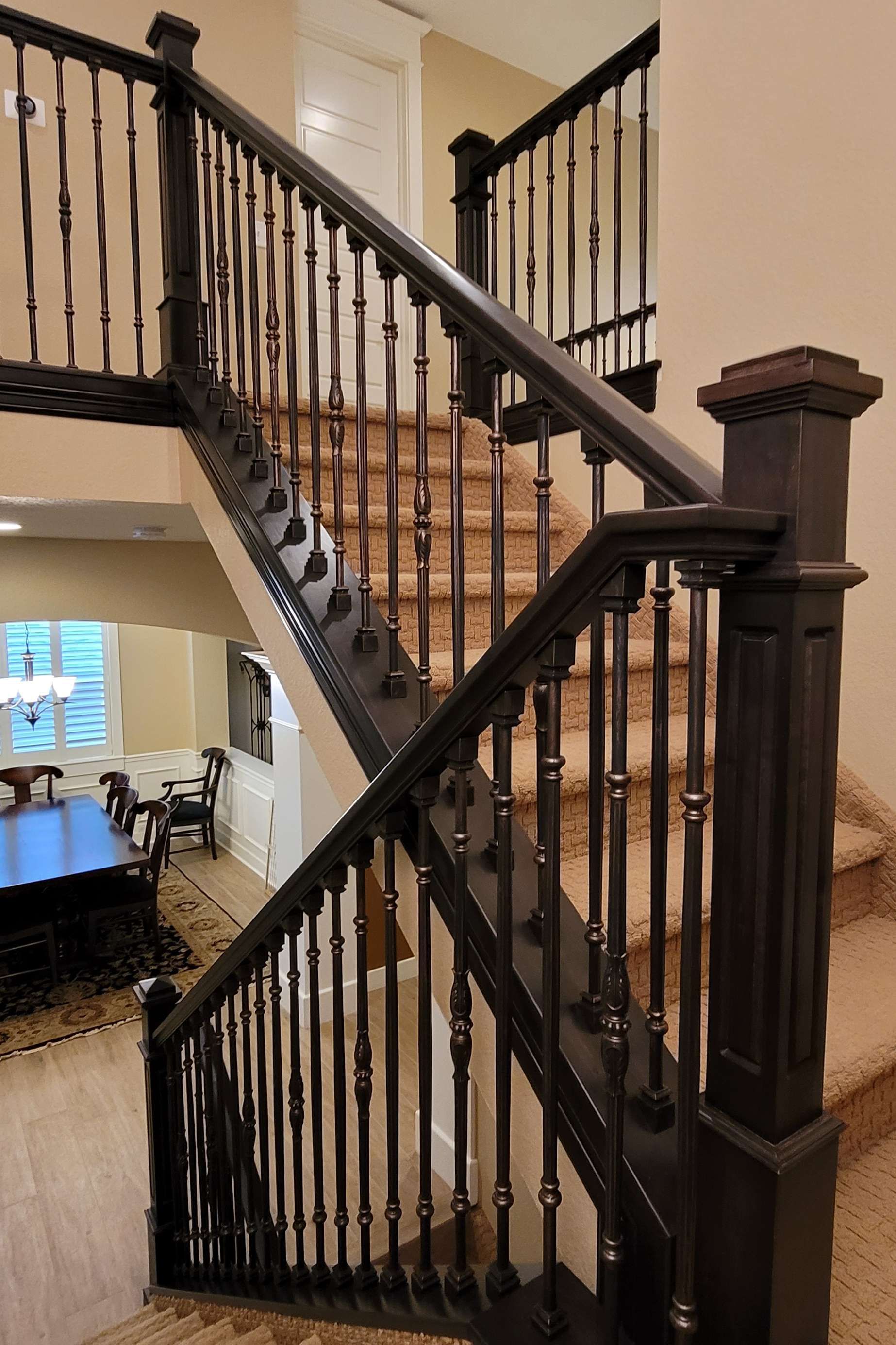 Dark wood staircase with beige carpet, leading to a second floor. The banisters and posts are prominent.