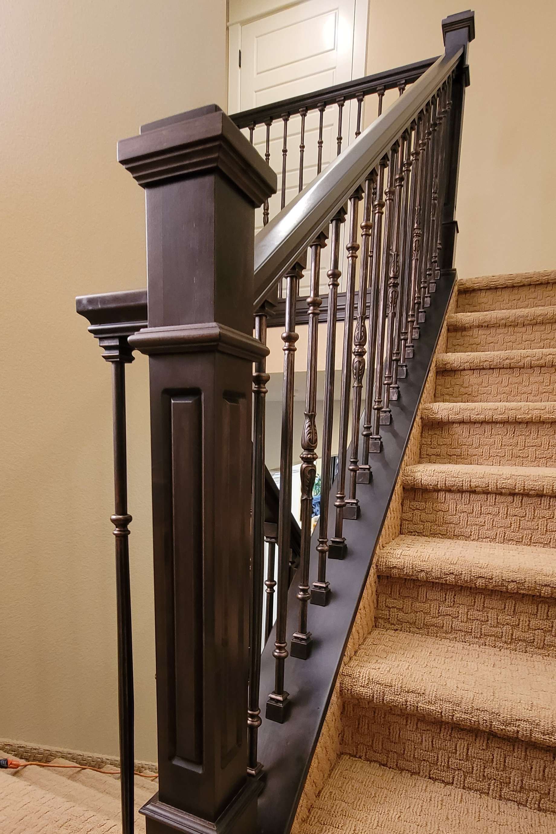 Brown staircase with carpeted steps and dark stained wooden banister.