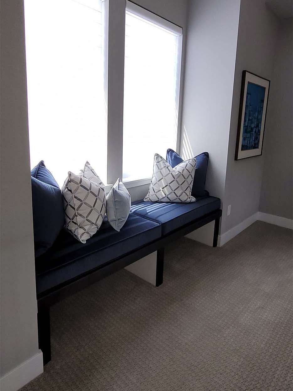 Window seat with navy cushions, decorative pillows, and a framed art print.