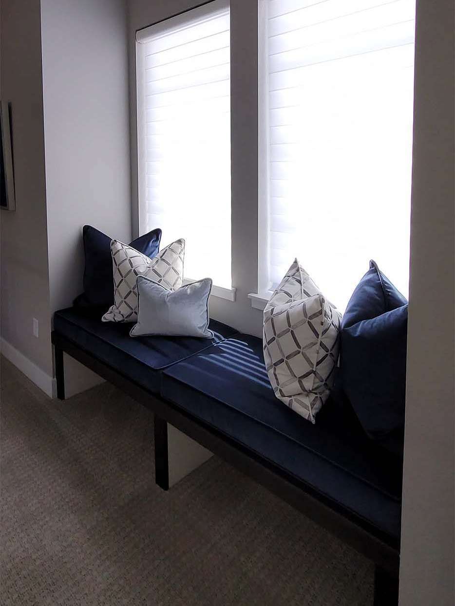 Window seat with navy cushions and patterned pillows.