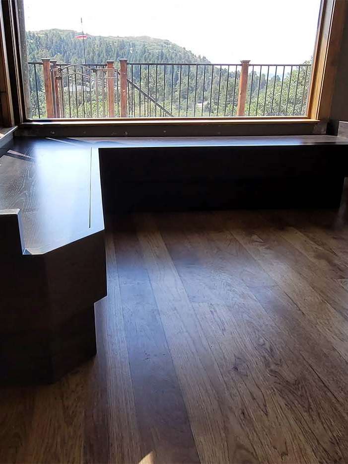 Wooden floor with a dark bench near a window overlooking a landscape.