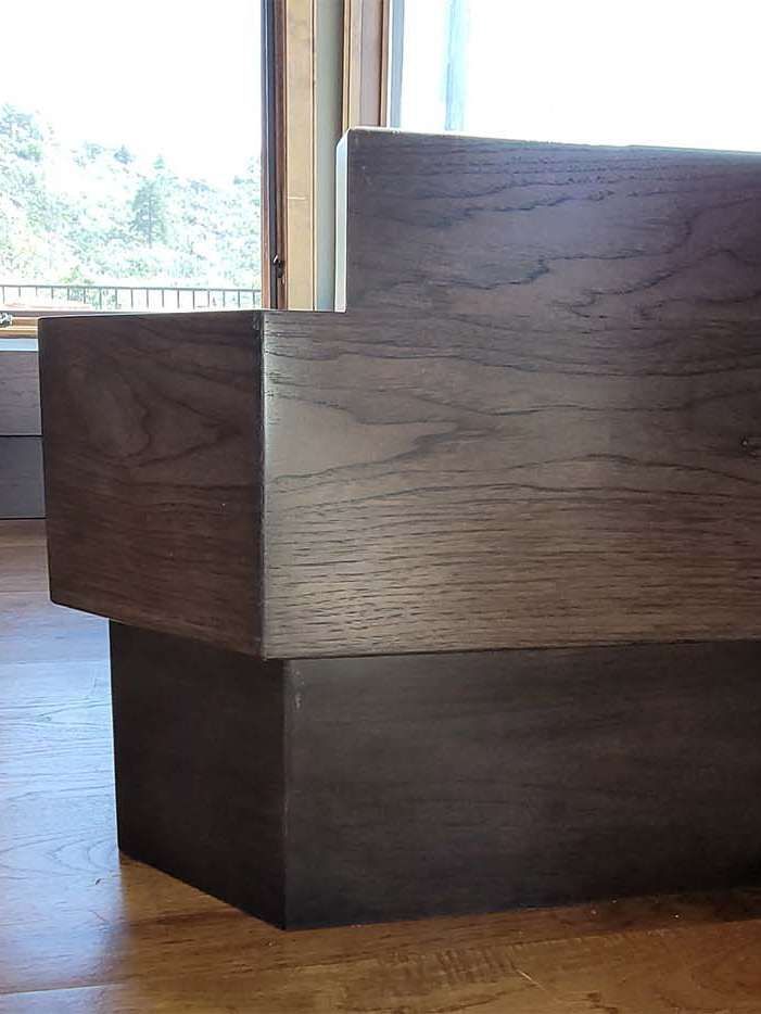 Dark wooden bed frame with stacked blocks, natural light.