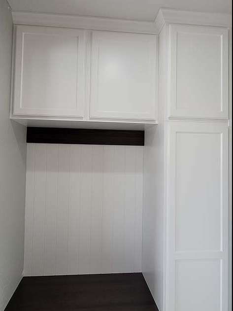 White kitchen cabinets above a dark countertop and backsplash.