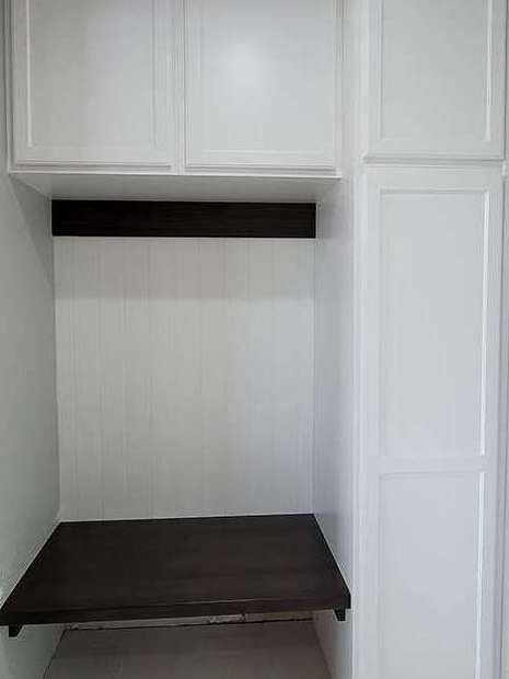 Built-in white cabinets with a dark brown desk and shelf.