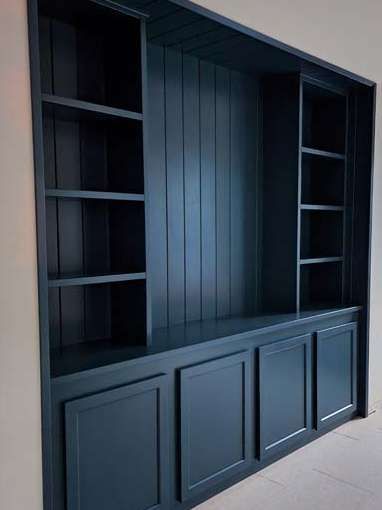 Built-in, dark blue bookcase with shelves and cabinet doors; set into a wall.