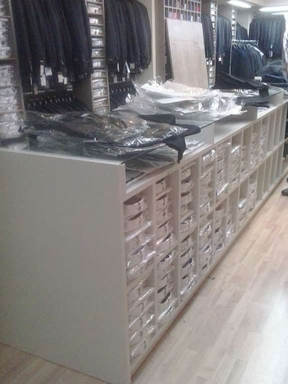 A long counter with many small, square compartments filled with boxes, presumably in a clothing store.