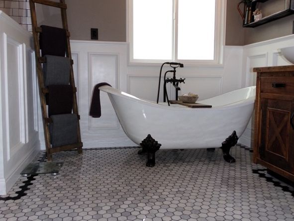 Bathroom with a white clawfoot tub, dark fixtures, and patterned tile floor.