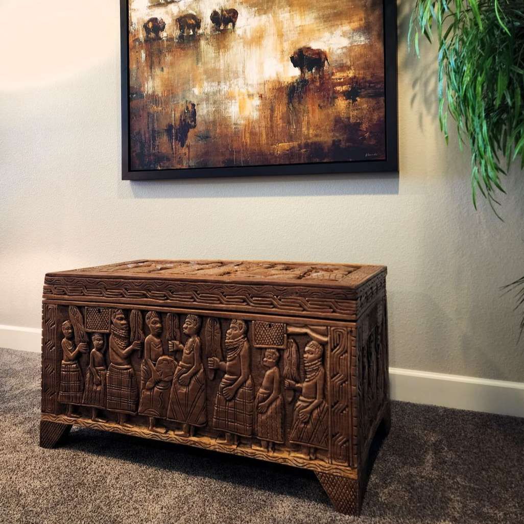 Carved wooden chest below an abstract painting, set against a neutral wall.