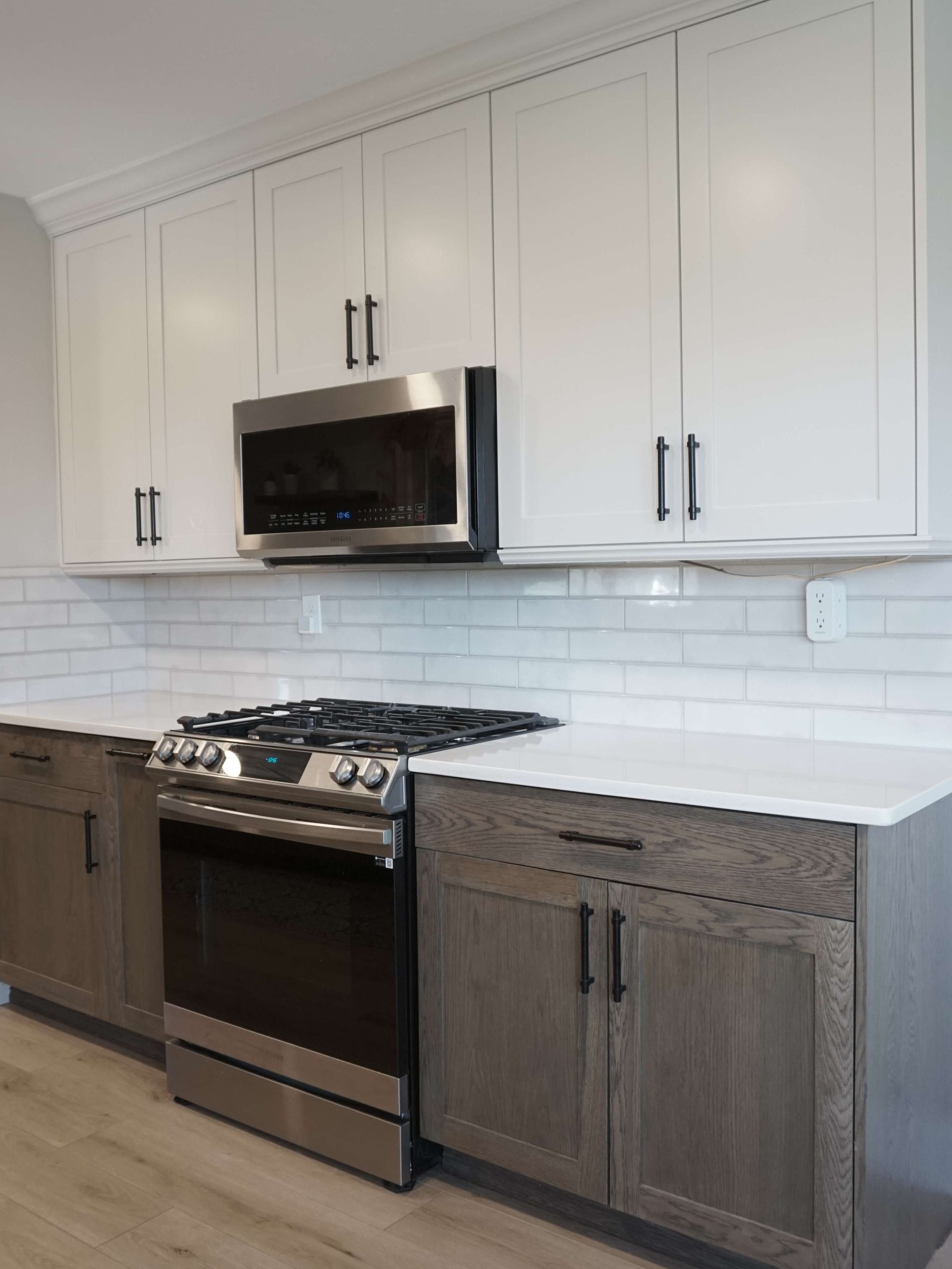 Kitchen with white upper cabinets and gray lower cabinets, stainless steel appliances, and white countertops.