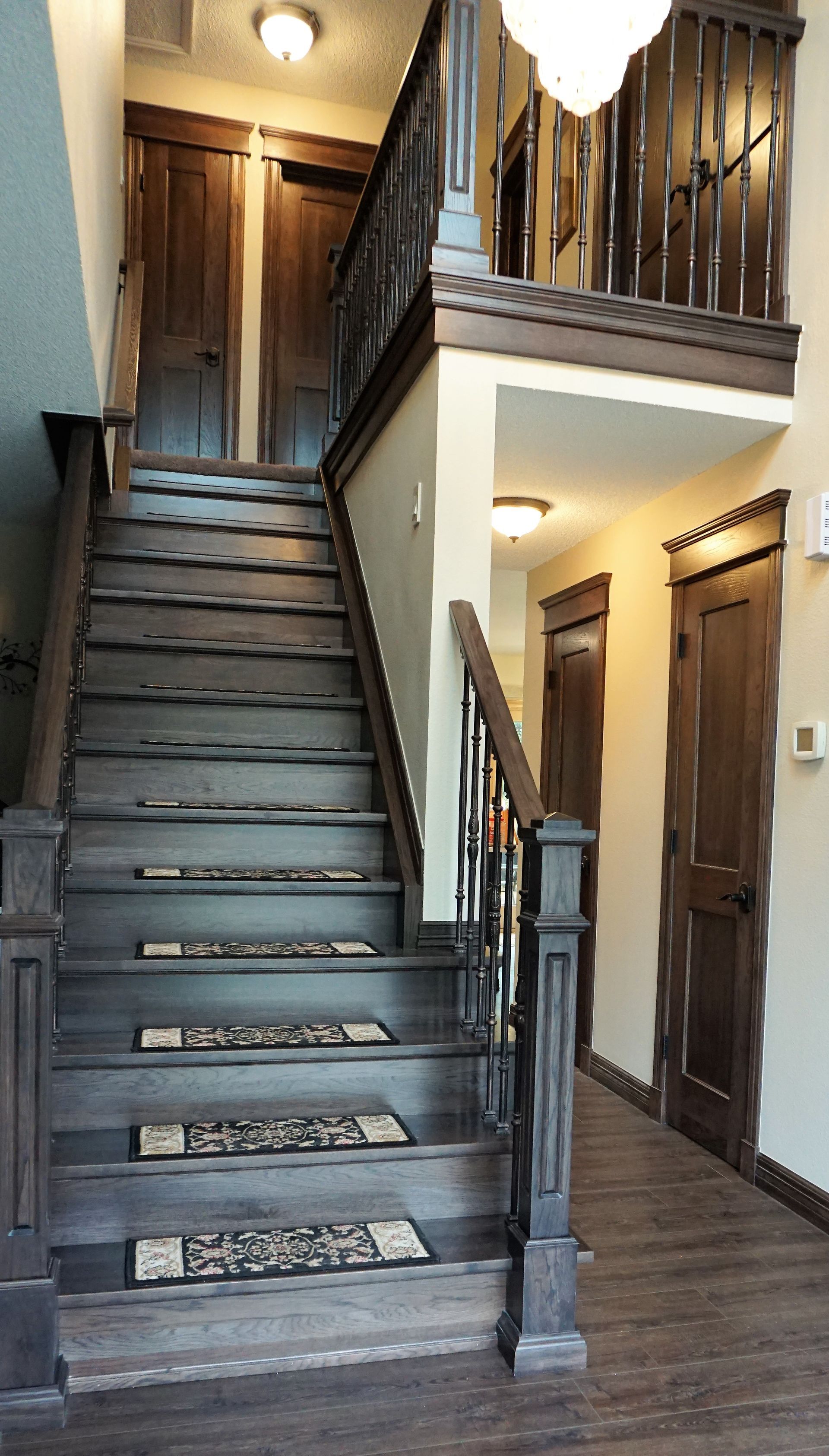 Wooden staircase with dark brown handrails, leading to a second floor landing with two doors.
