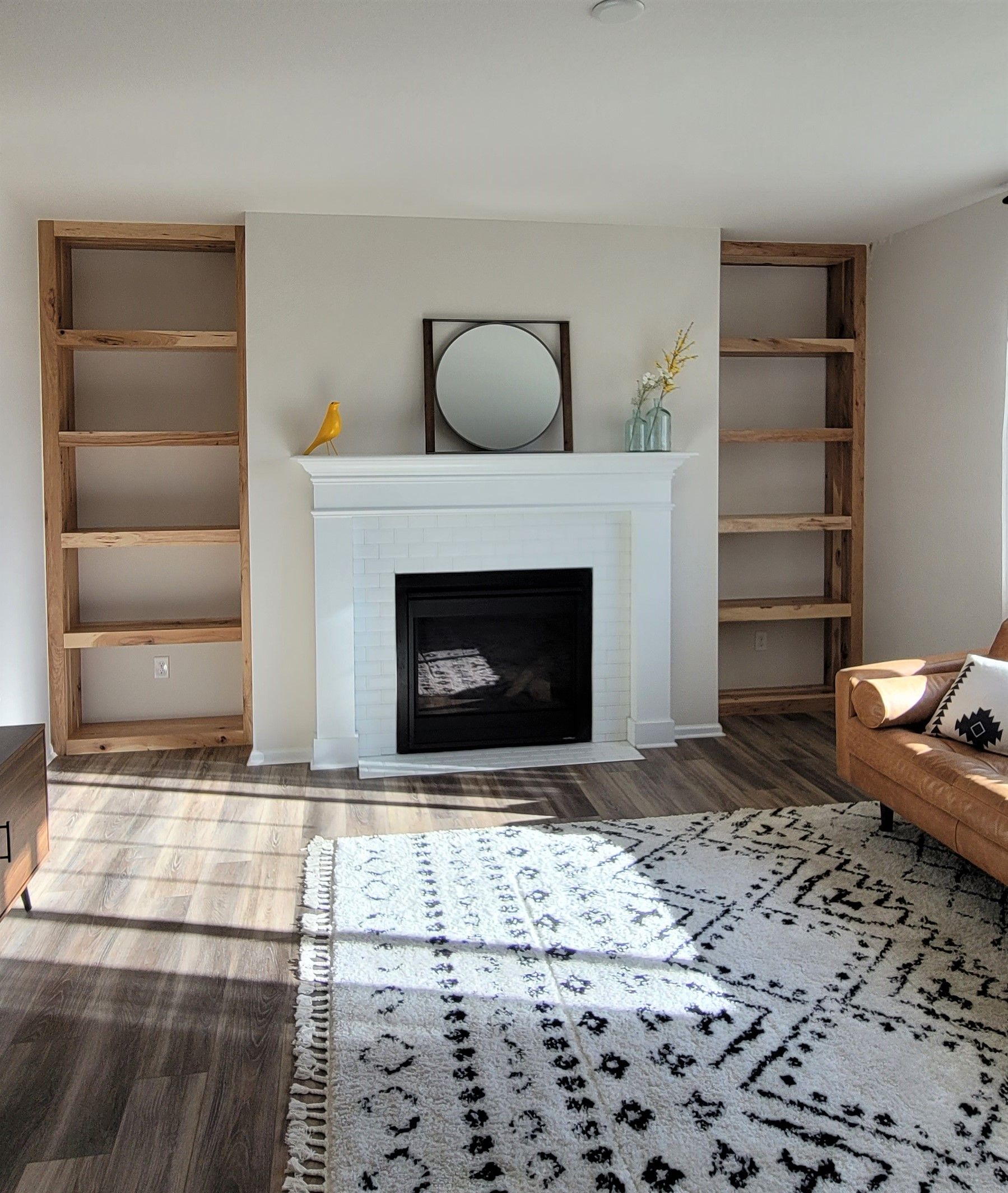 Living room with fireplace, bookshelves on either side, rug, and leather couch.