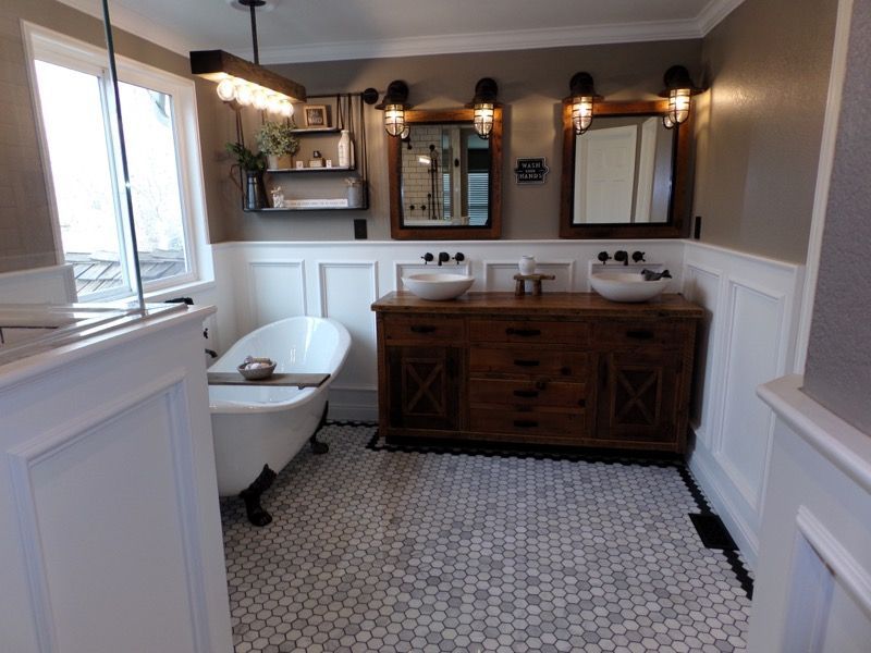 Bathroom with white tile floor, wooden vanity with vessel sinks, clawfoot tub, and two mirrors.
