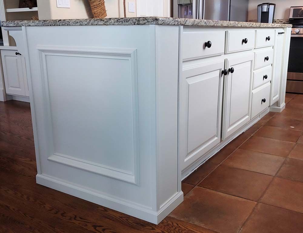 White kitchen island with granite countertop, cabinets, and drawers.