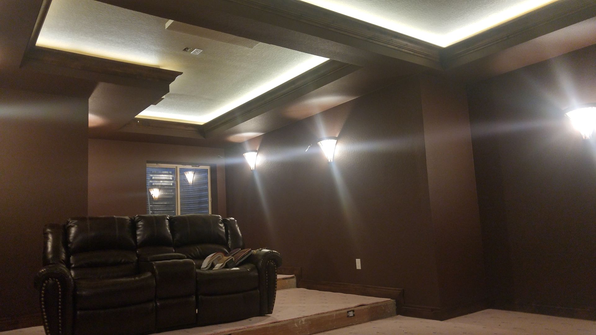Brown home theater with recliner couch and recessed lighting.