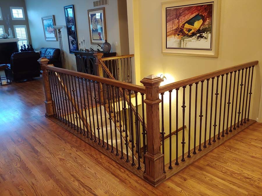 Wooden staircase with dark metal spindles and artwork on the wall.