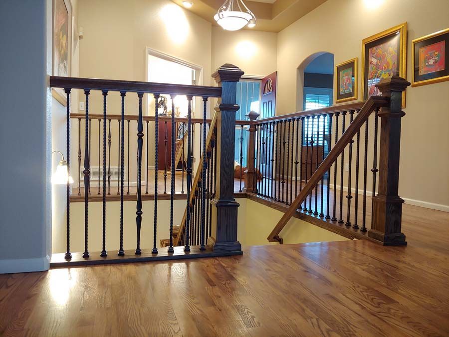 Wooden staircase with dark brown banister, leading down to a lower level in a home.