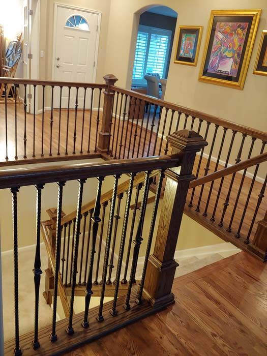 View of a two-story home's wooden staircase with dark spindles and railing, leading to the entrance.