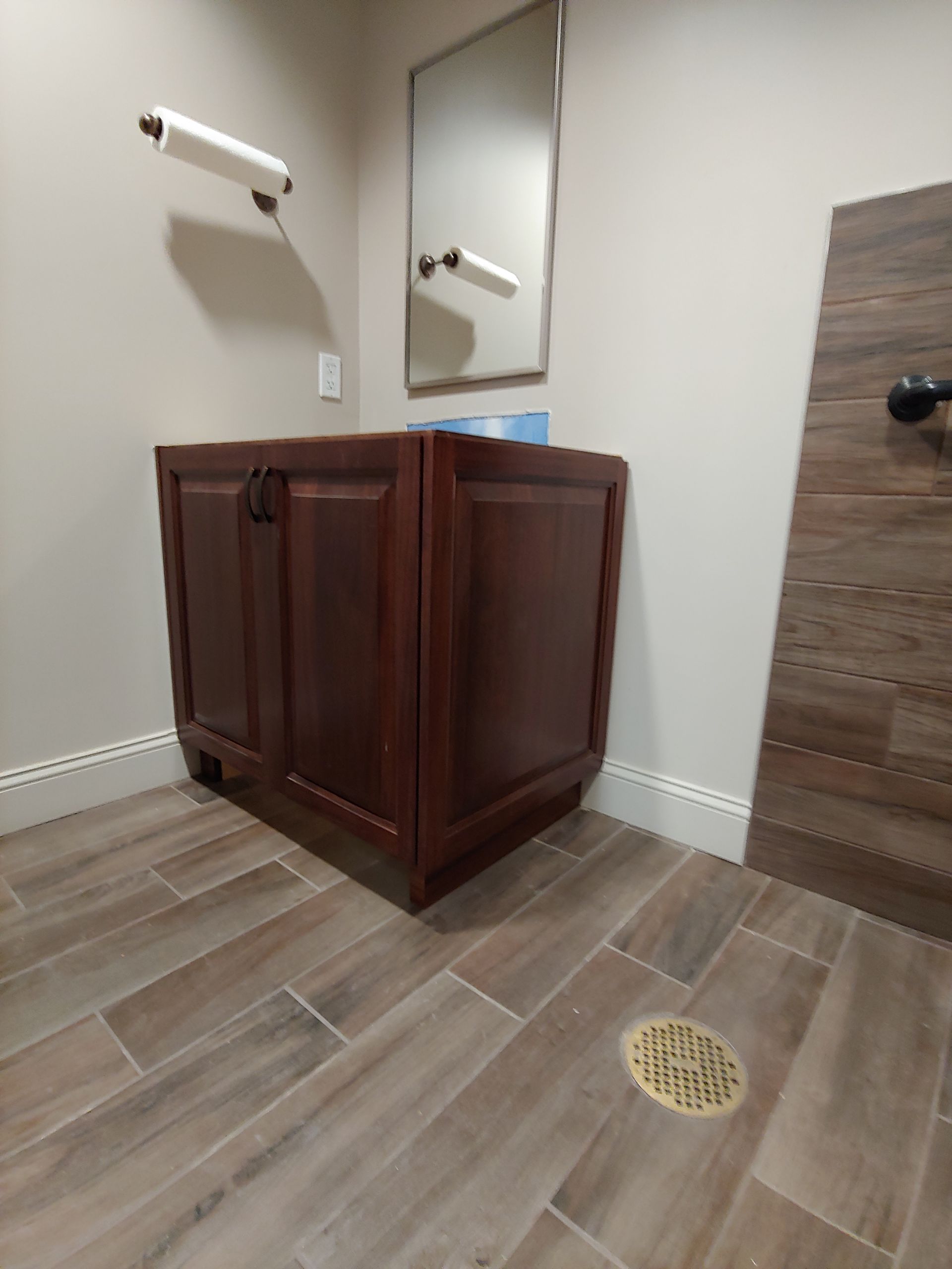Bathroom with a dark wood vanity, wood-look tile floor, and a mirror.