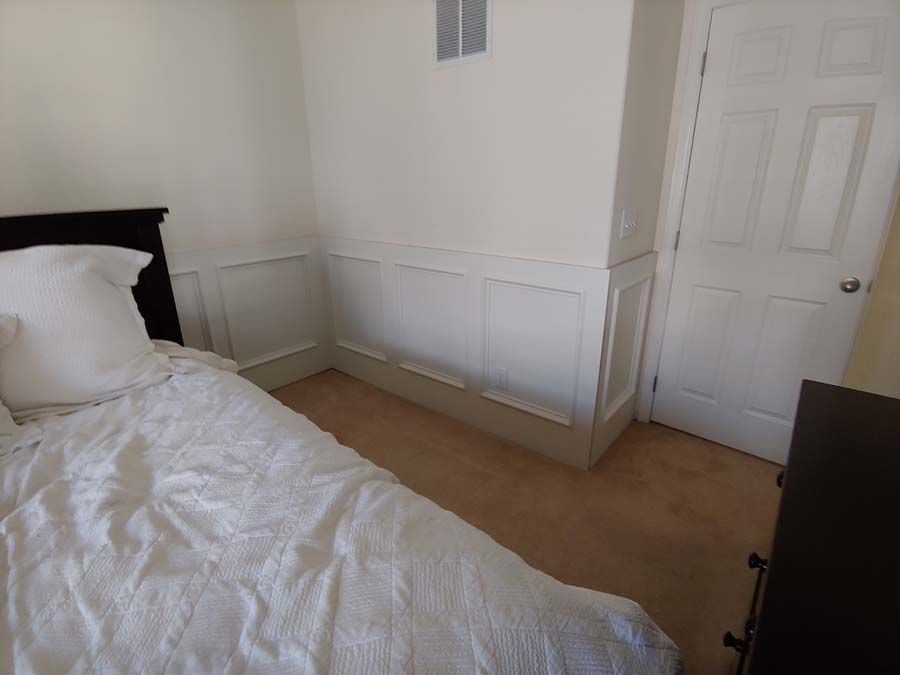 Bedroom with white walls, a bed with white bedding, and a brown carpet.