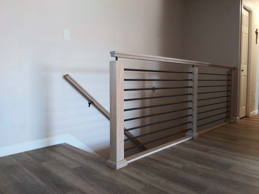 Wooden and black metal horizontal railing in a hallway.